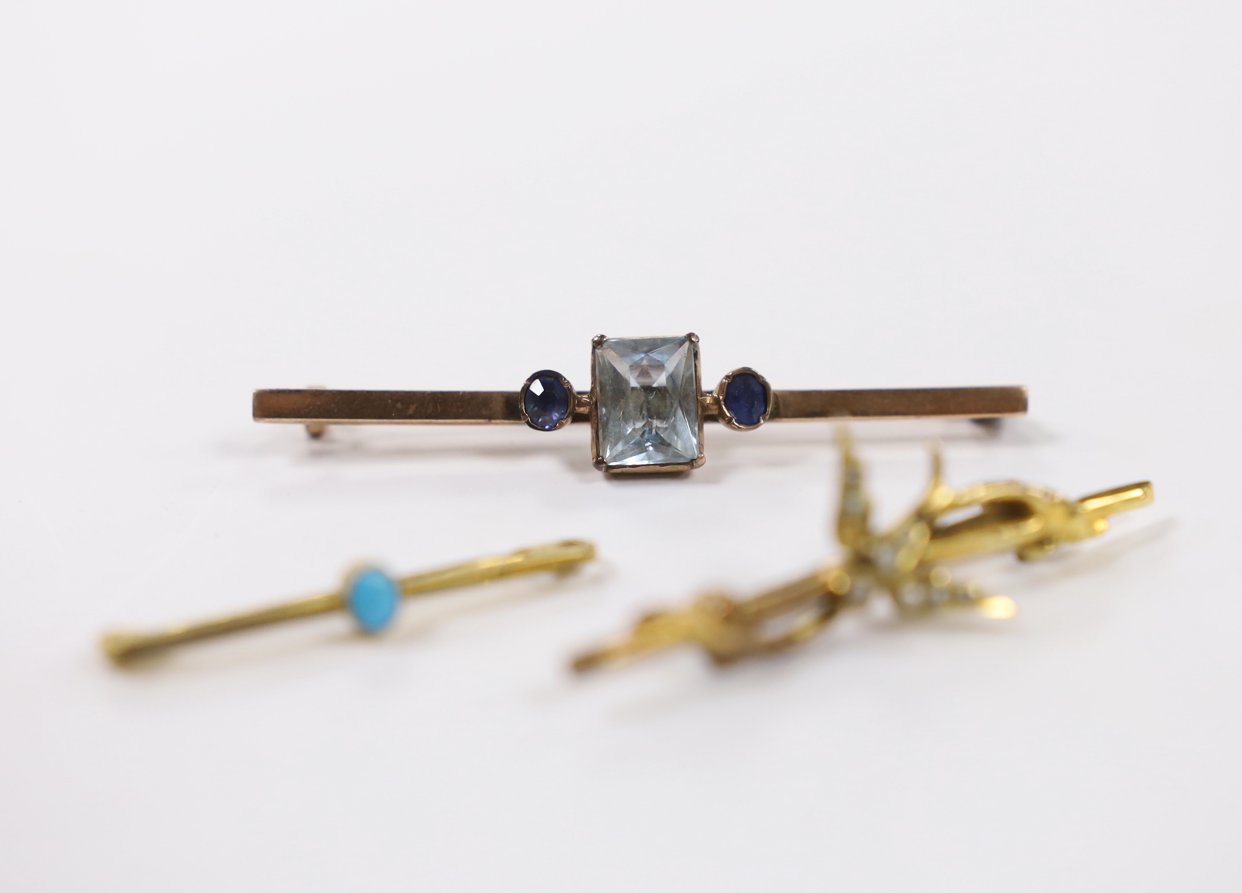 An Edwardian 9ct gold and seed pearl set swallow bar brooch, 43mm, a 9ct gold and turquoise set tie pin and a yellow metal, single stone aquamarine and two stone sapphire set bar brooch.